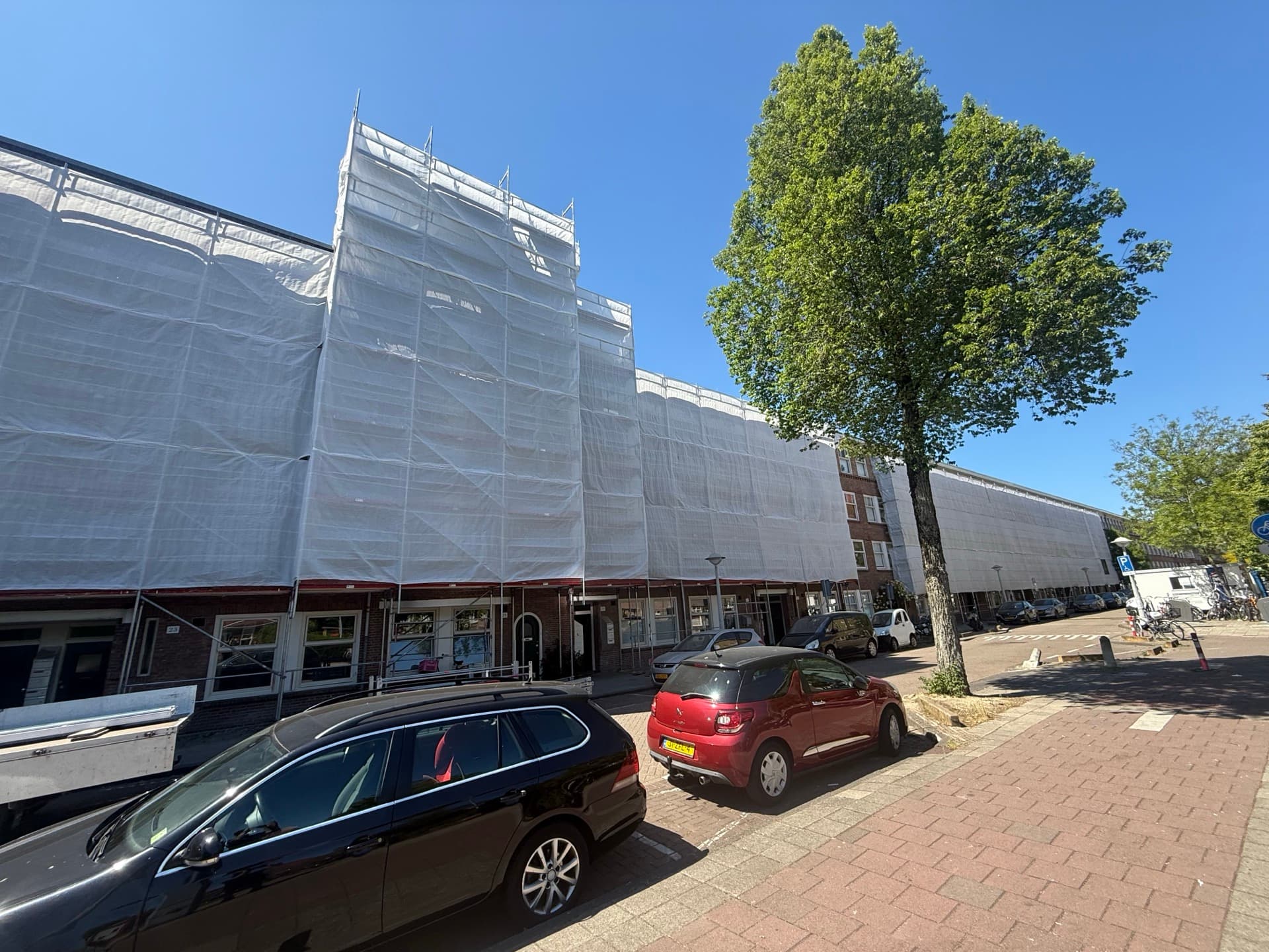 Grootschalige gevelrenovatie van appartementencomplex met volledig ingepakte steiger