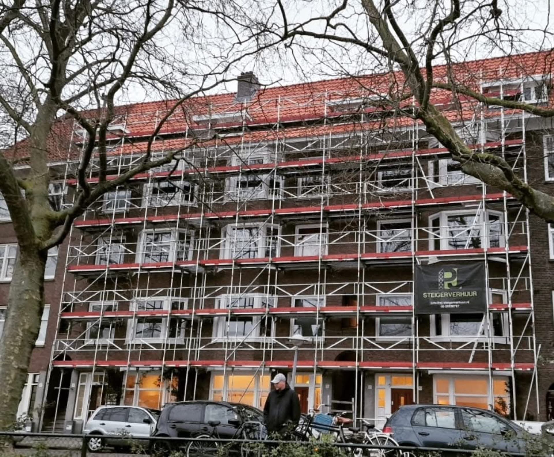 Gevelsteiger met PJ Steigerverhuur banner bij appartementencomplex renovatie