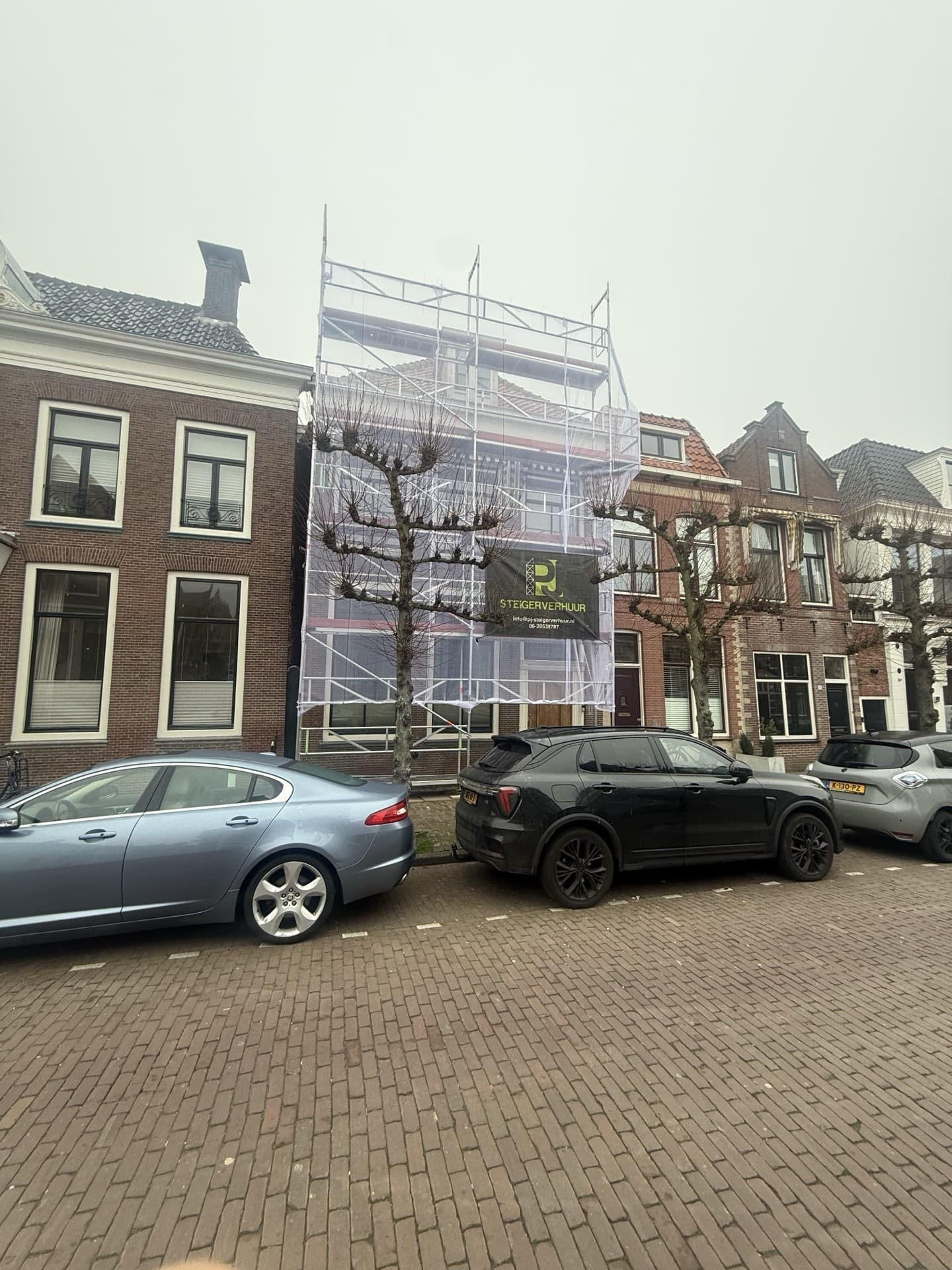 Gevelsteiger met PJ Steigerverhuur spandoek bij woningbouw renovatieproject