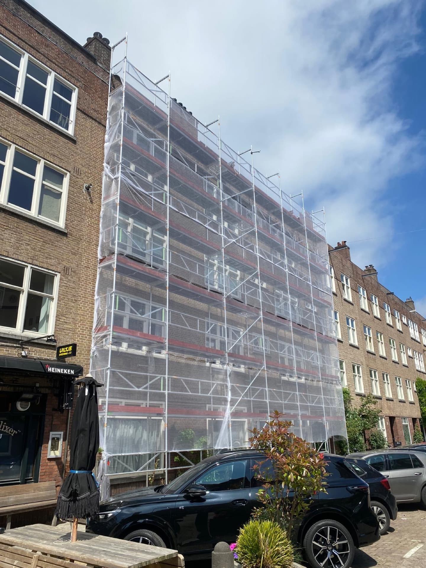 Gevelsteiger met transparant veiligheidsnet bij appartementencomplex